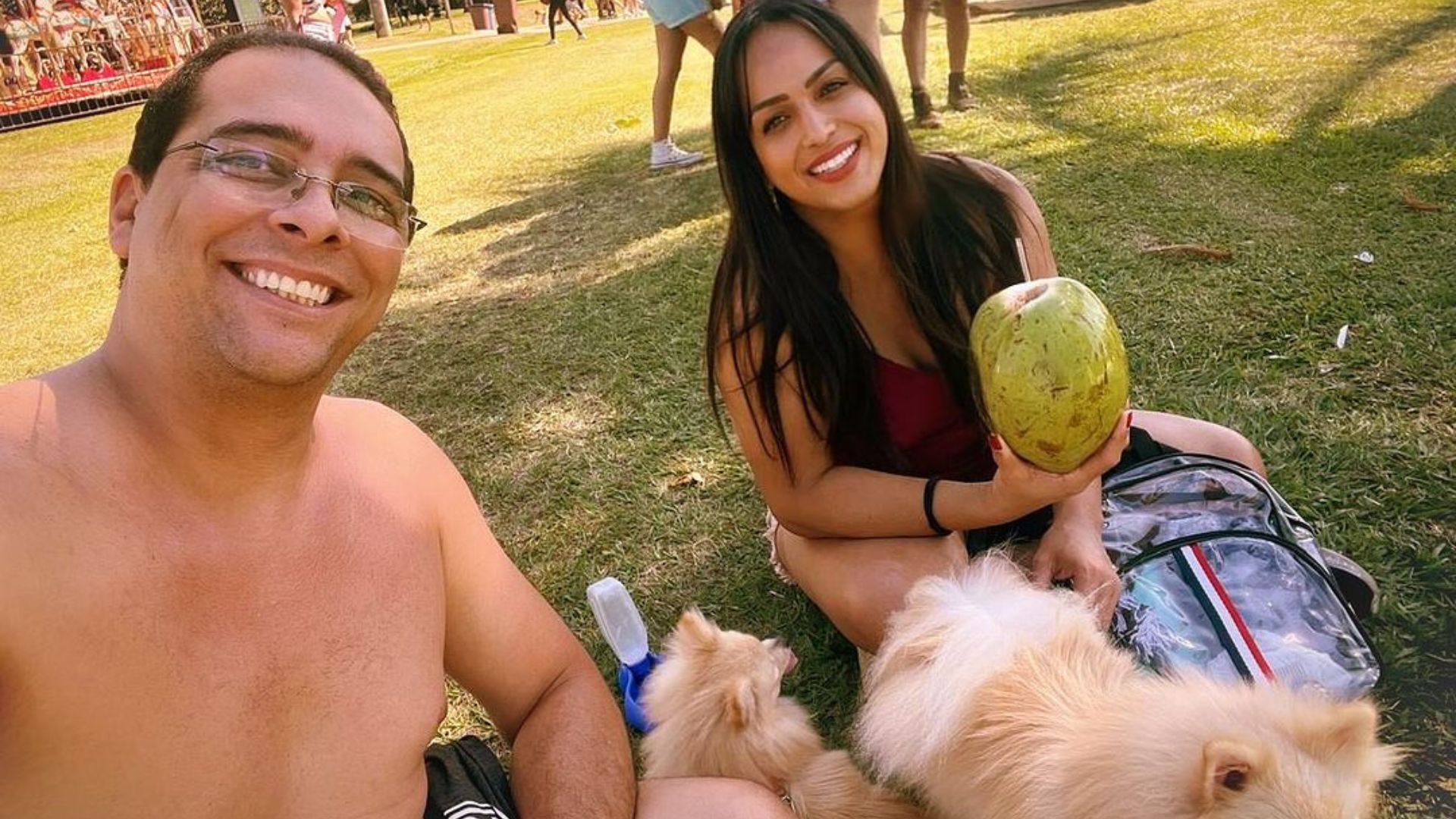 Casal em um parque tomando água de coco com cachorros