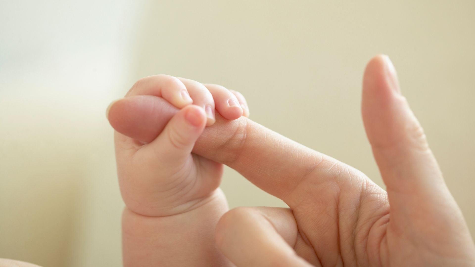Mãe de bebê segurando dedo da mãe