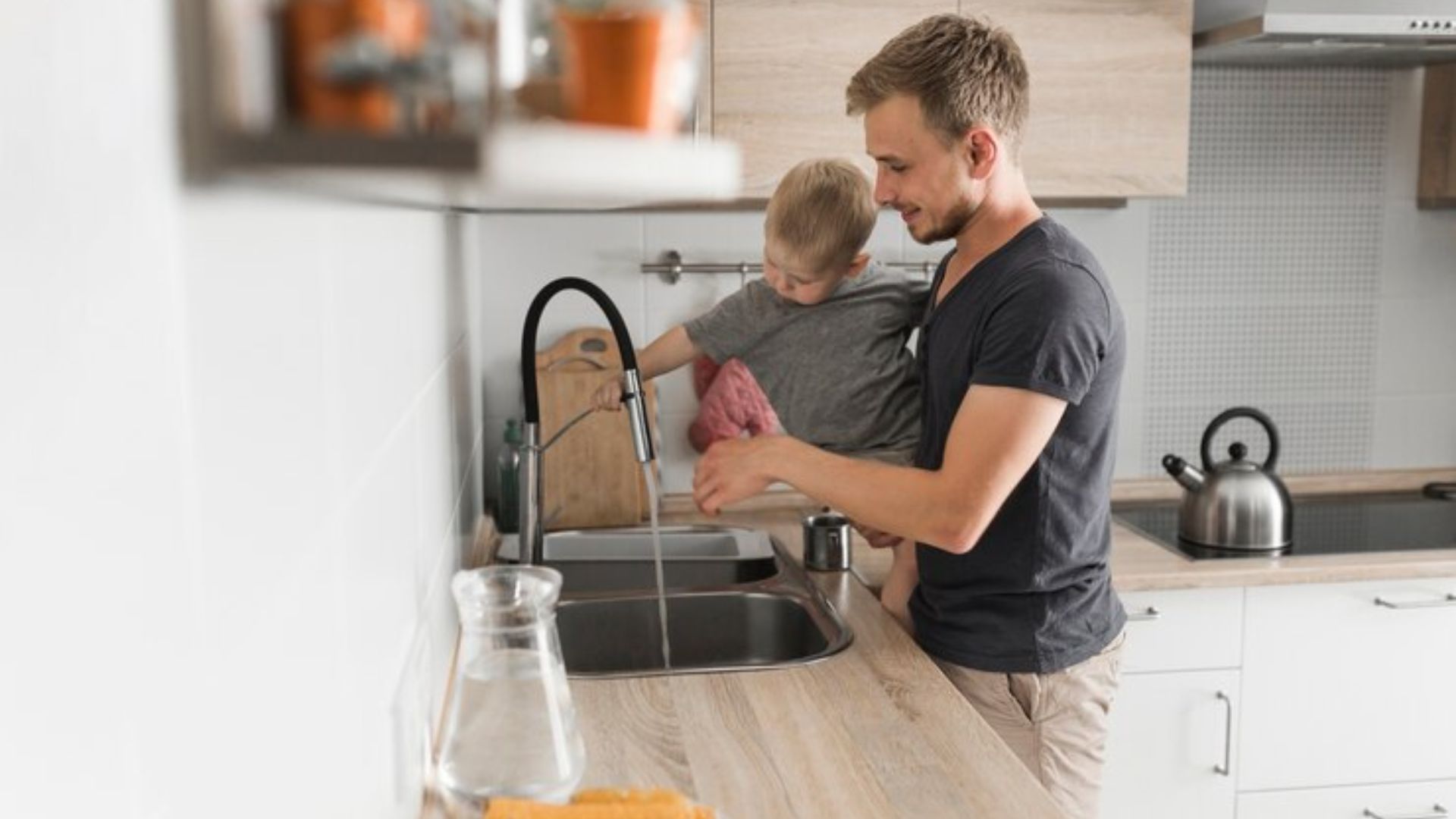 Homem lavando louça com criança no colo