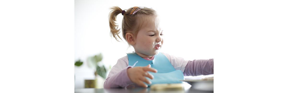 Little girl toddler picking her food, making faces. Childhood problems, picky eater, eating habits, terrible two concept.