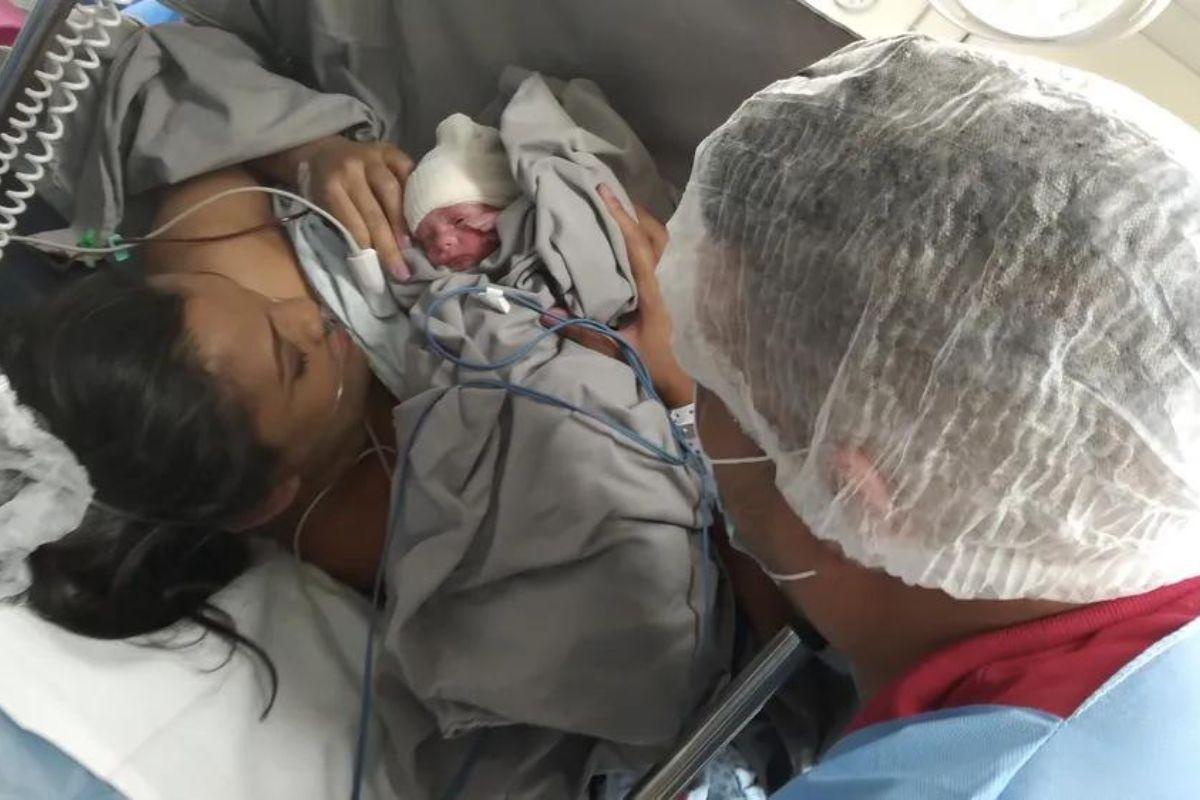 Érika da Silva, mãe dos trigêmeos, com seu marido e seu filho Gustavo em seu colo, logo após o parto.