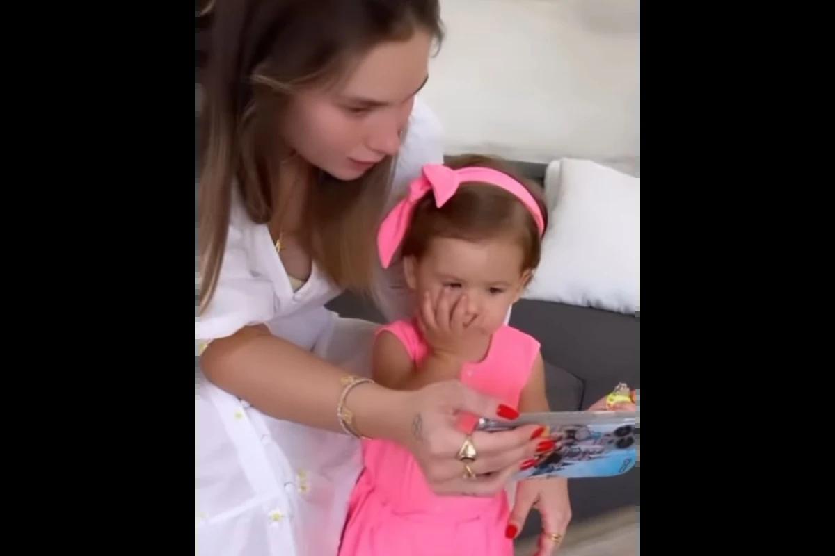 Mulher branca com blusa branca e menina de 1 ano com roupa rosa
