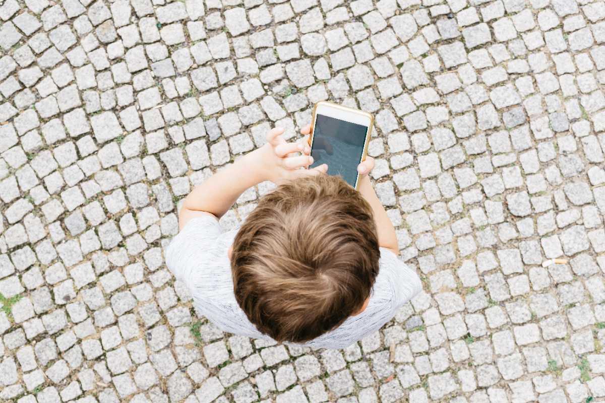 Criança mexendo no celular vista de cima