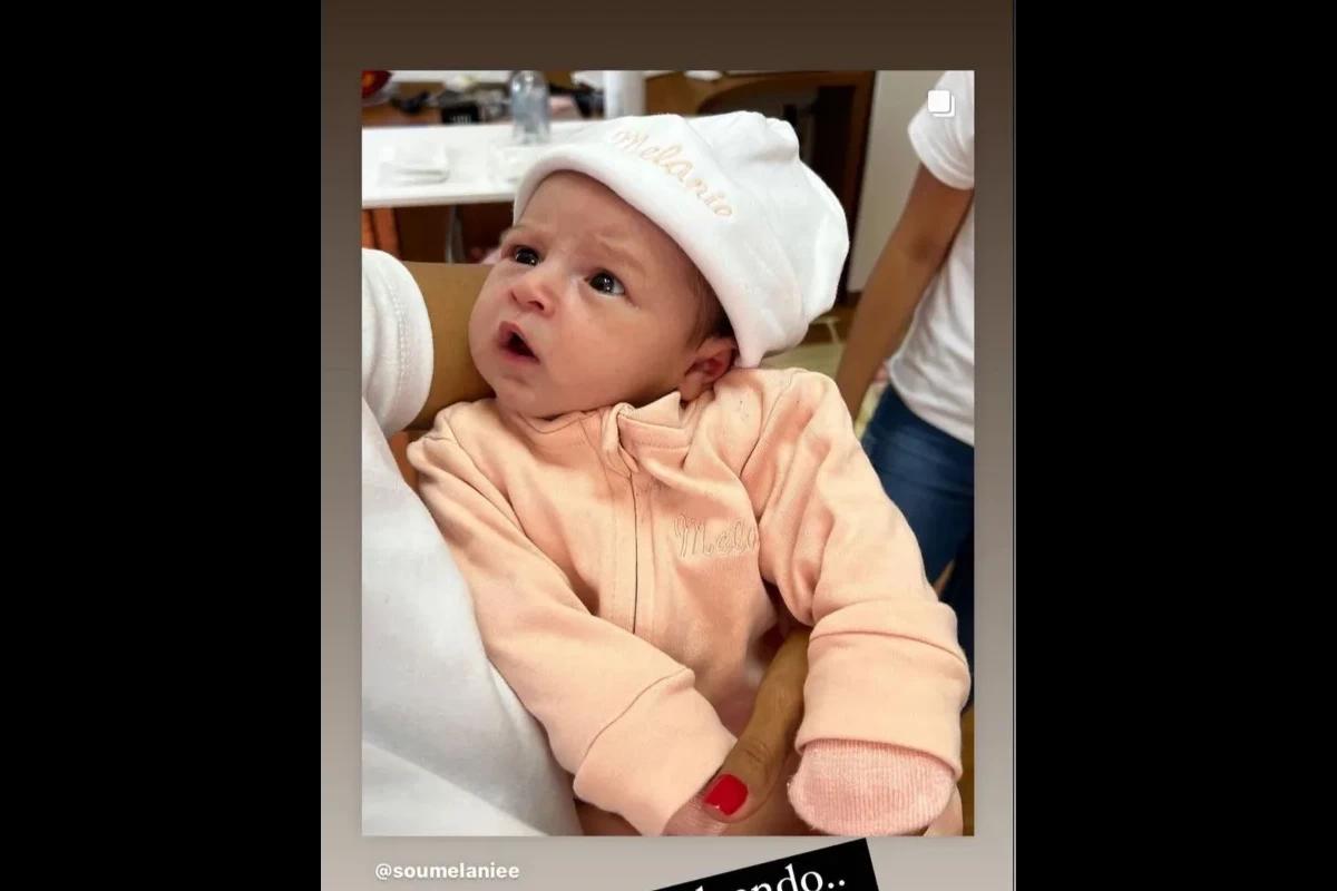 Bebe usando macação salmão e toca branca