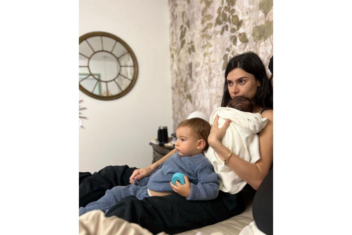 Thaila Ayala sentada na cama com os dois bebês