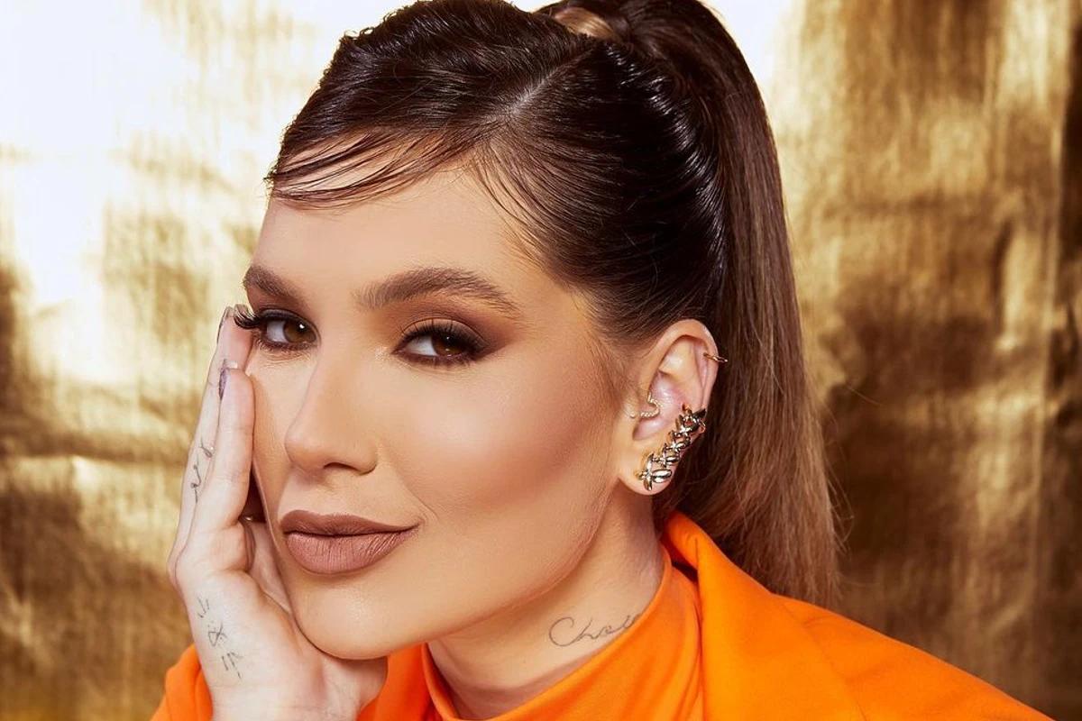 Virginia maquiada com cabelo preso e fundo dourado