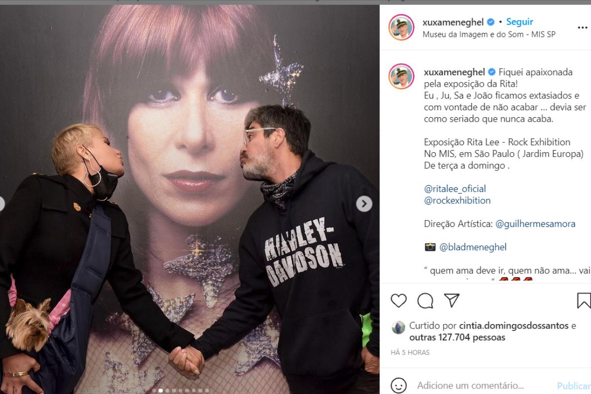 Xuxa dando às mãos ao parceiro, Junno Andrade, durante exposição em homenagem à Rita Lee