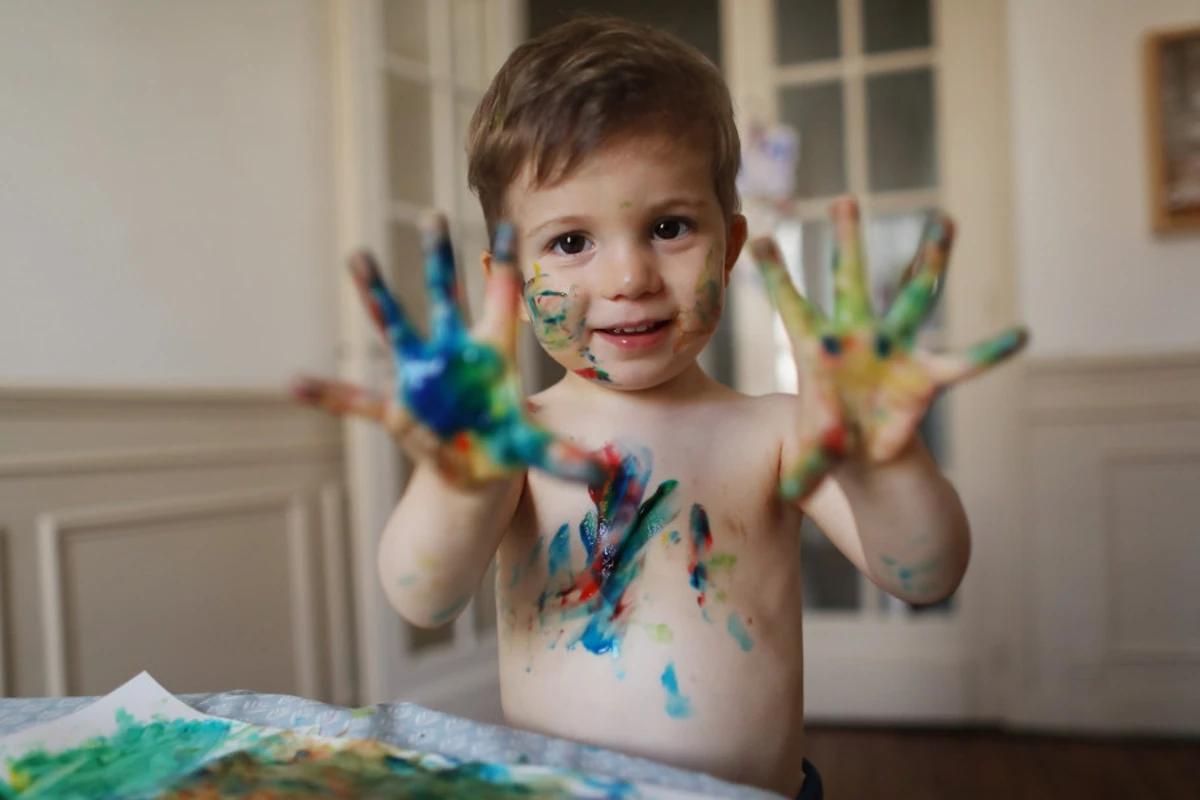 Criança com as mãos cheias de tinta
