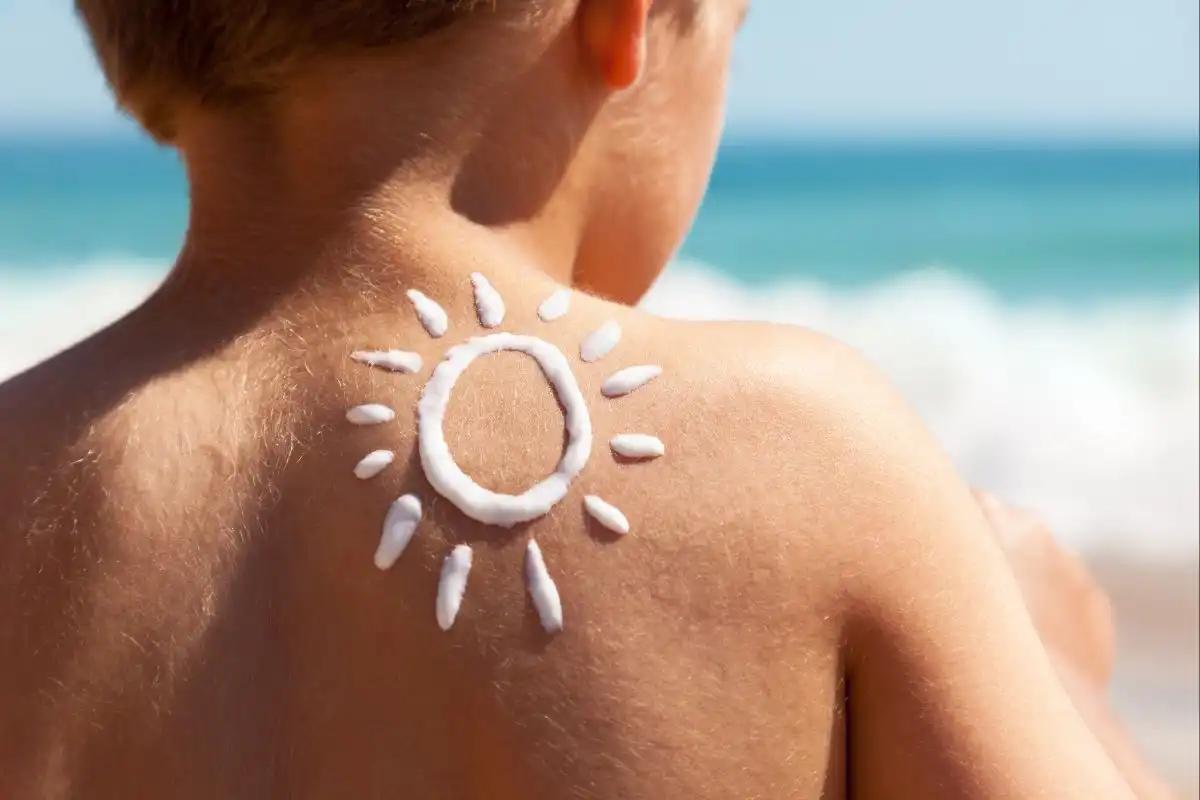 Criança de costas no sol com protetor para falar sobre cuidados com pele no verão