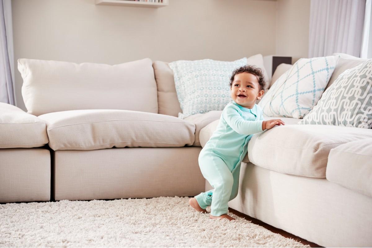 Bebê apoiado no sofá em pé