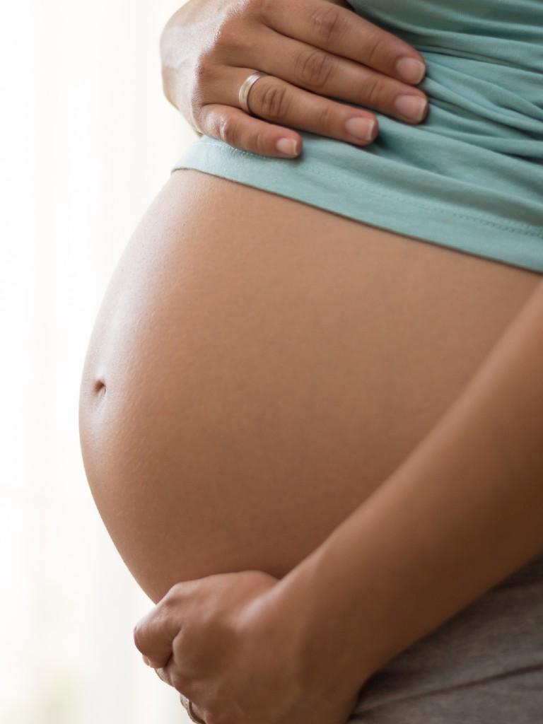 mulher grávida com as mãos na barriga