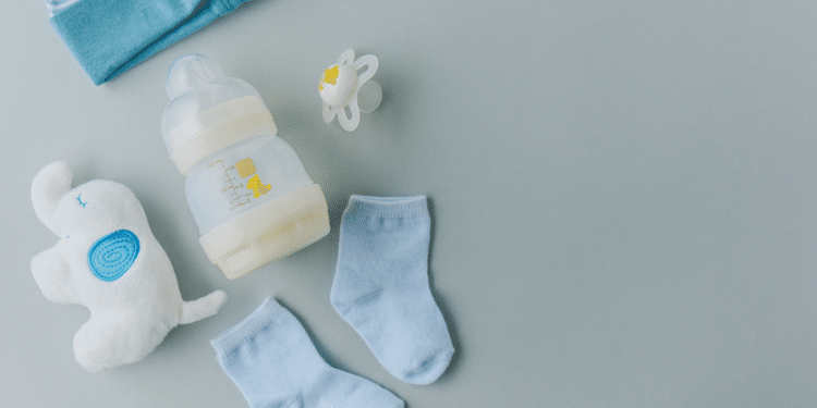 Mamadeira, chupeta, meias e brinquedo de bebê em fundo cinza