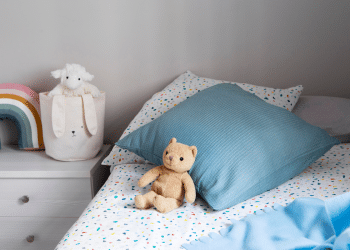 cama de criança com um ursinho bege.