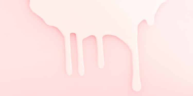 Leite derramado em um fundo rosa, representando a amamentação.