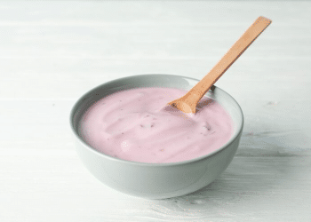 Bowl com uma colher apoiada. Dentro tem danone rosa