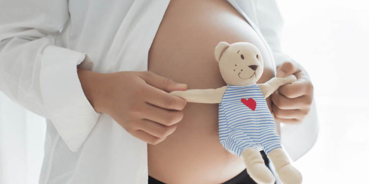 Barriga de grávida com um ursinho na frente.