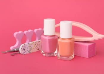 Esmaltes e utensílios de unha em fundo rosa.