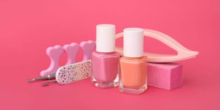 Esmaltes e utensílios de unha em fundo rosa.