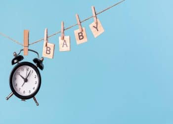 Um relógio e letras de madeira pendurados em uma corda.