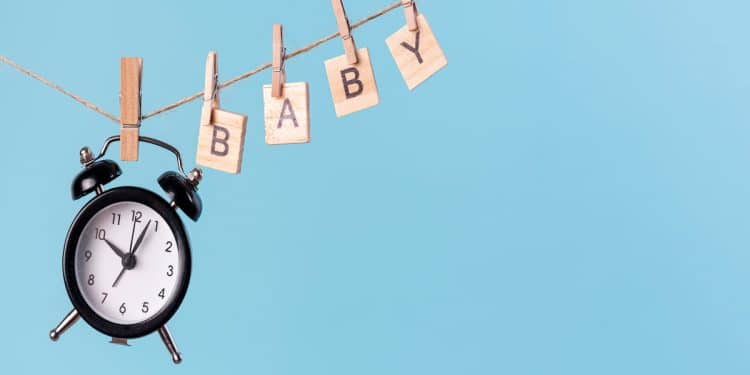 Um relógio e letras de madeira pendurados em uma corda.