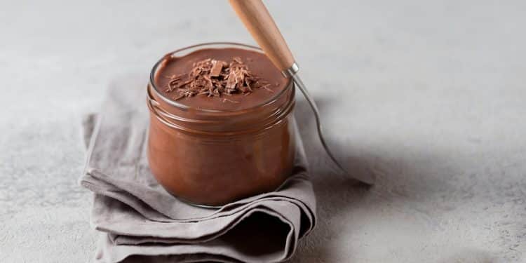 Mousse de chocolate no copo em cima de um pano e ao lado de uma colher.