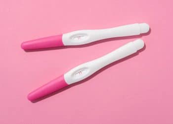 Testes de gravidez em fundo rosa, representando o início da gestação.