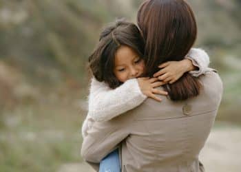 Mãe segura sua filha no colo.
