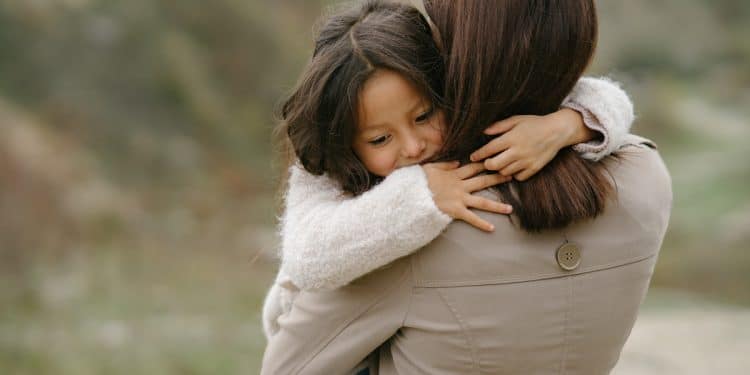 Mãe segura sua filha no colo.