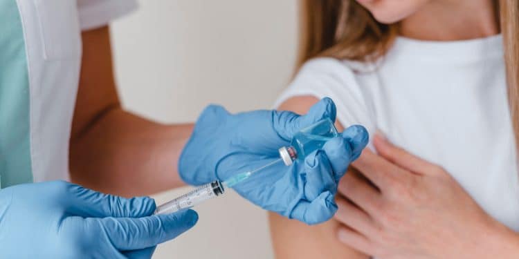 Profissional da saúde preparando vacina para uma paciente.