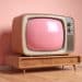 Televisão retrô com tela rosa em frente a parede rosa.