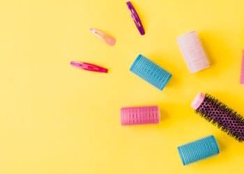 Escova e bobes de cabelo em um fundo amarelo.