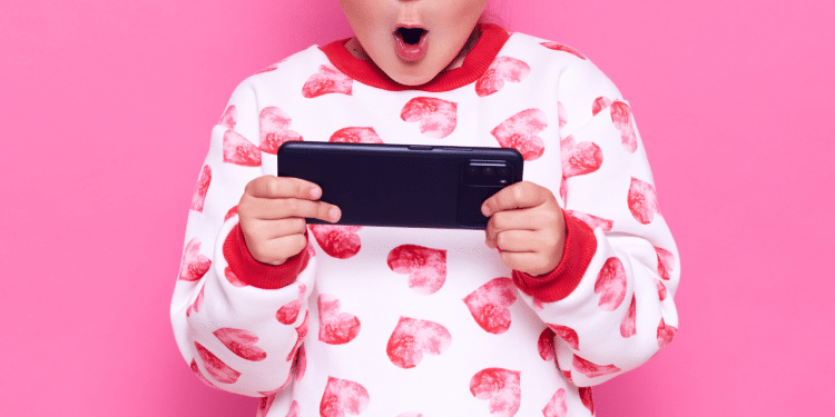 Criança com celular na mão e um pijama rosa e branco