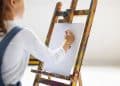 Criança pintando sua obra de arte em uma tela no cavalete.