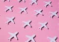 Aviões de papel em fundo rosa representando o jet lag.