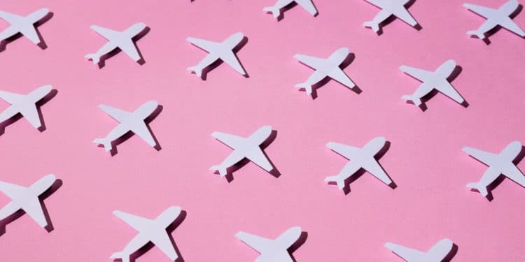 Aviões de papel em fundo rosa representando o jet lag.