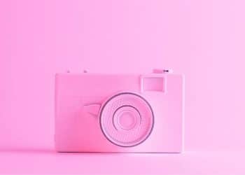 Câmera rosa bebê em frente a um fundo da mesma cor, representando um ensaio fotográfico infantil.