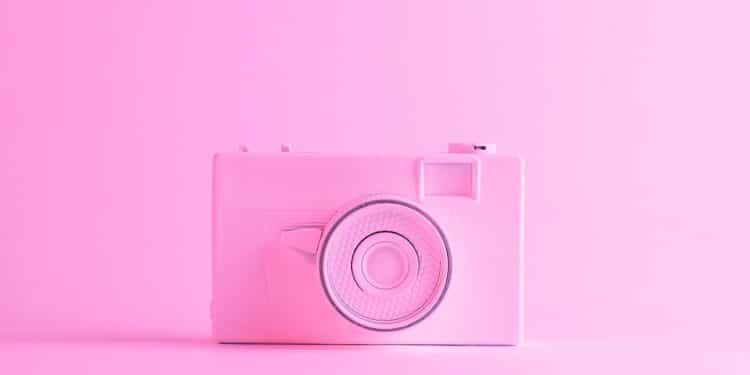 Câmera rosa bebê em frente a um fundo da mesma cor, representando um ensaio fotográfico infantil.