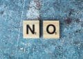 Letras de madeira formando a palavra "no", representando a disciplina de um filho.