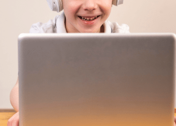 Criança olhando para o computador e sorrindo
