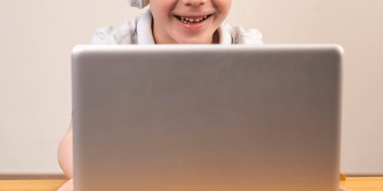 Criança olhando para o computador e sorrindo