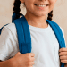 Criança com uma camisa branca sorrindo com uma mochila nas costas