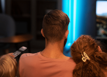 Um pai, uma mãe e um filho assistindo alguma coisa na televisão