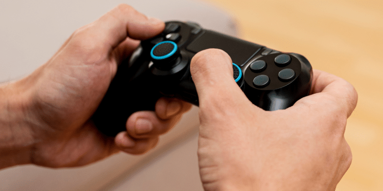 Uma mão segurando um controle de viedeogame preto