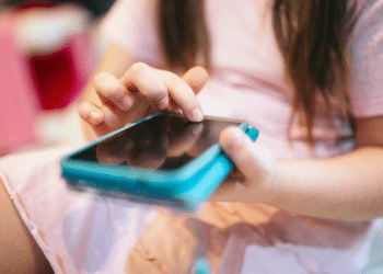 criança com um celular na mão com uma capinha azul