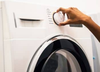 Máquinha de lavar, cm uma mão segurando o botão