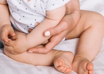 Bebê segurando a barriga, aparentemente com dores intestinais.