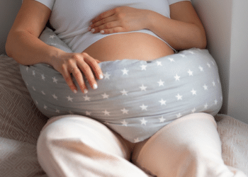 Barriga de uma mulher grávida, deitada com um travesseiro