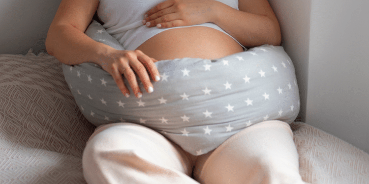 Barriga de uma mulher grávida, deitada com um travesseiro