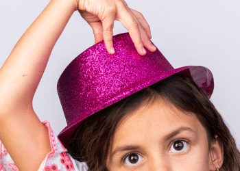 Criança com um chapéu rosa e com a mão encima dele