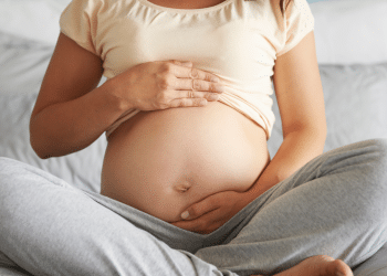 Mulher grávida sentada e segurando a sua barriga como se estivesse acariciando